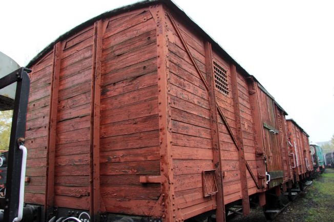 Wagon kryty o konstrukcji drewnianej stoi na torach kolejowych; wyposażony jest w dwa zestawy kół oraz drzwi umieszczone po bokach. Elementy metalowe takie jak okucia i osprzęt są widoczne na całej długości pojazdu. Drewniana powierzchnia zewnętrzna jest pomalowana na czerwono, a wagon pokryty jest dwuspadowym dachem.