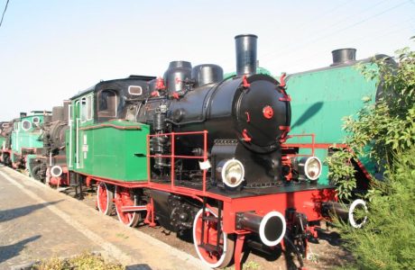 The black and green steam locomotive with one driving axle and a large tender stands on the tracks. It has a round chimney and classic steam locomotive elements: wheels, drive rods, and high cylinder covers. It is carefully restored and can be a museum exhibit or tourist attraction.