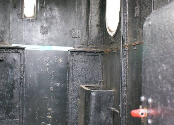 Wewnątrz lokomotywy parowej widoczna jest kabina maszynisty z metalowymi panelami na ścianach i urządzeniami sterowniczymi. Po lewej stronie kabiny umieszczony jest okrągły piec, obok którego znajduje się uchwyt w kolorze czerwonym. Światło wpada przez okrągłe okno i kwadratową szybę umieszczoną na wprost wejścia do kabiny.