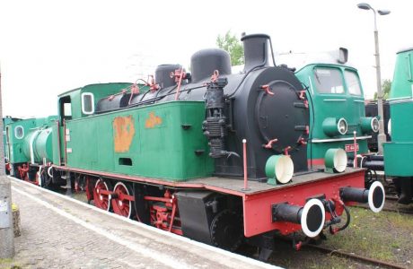 The green steam locomotive with red trim is standing on the railway tracks; the TKp 4147 model comes from a Belgian factory from the time of World War II. The boiler of the locomotive, round cabin windows, and large wheels are characteristic details of this type of vehicle. The vehicle is part of a series designed for shunting work in industry and uses saturated steam.