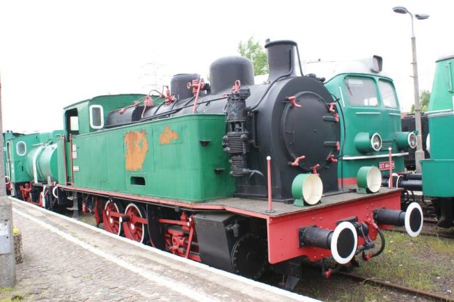 Zielona lokomotywa parowa z czerwonymi obramowaniami stoi na torach kolejowych; model TKp 4147 pochodzi z belgijskiej wytwórni z czasów II wojny światowej. Kocioł lokomotywy, okrągłe okna kabiny oraz duże koła są szczegółami charakterystycznymi dla tego typu pojazdu. Pojazd jest częścią serii przeznaczonej do prac manewrowych w przemyśle i wykorzystuje parę nasyconą.