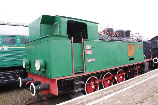 Zielona lokomotywa parowa z czerwonymi obręczami kół stoi na szynach. Posiada prostokątny zbiornik wodny i czarny komin. Numer 4147 jest widoczny na boku lokomotywy.