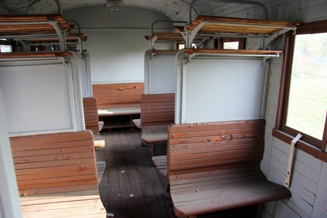 Wewnątrz wagonu widać drewniane ławki ułożone wzdłuż okien, skonstruowane tak, że pasażerowie siedzą naprzeciwko siebie. Nad siedzeniami znajdują się bagażowe półki również wykonane z drewna. Podłoga jest drewniana i widoczne są ślady użytkowania.