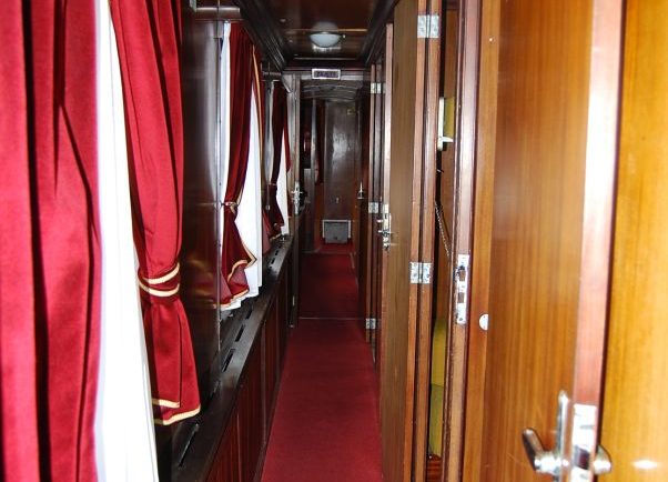 Wewnątrz wagonu salonowego zaobserwować można ciemne, drewniane okładziny ścian i czerwony dywan rozciągnięty wzdłuż wąskiego korytarza. Po obu stronach korytarza znajdują się drewniane drzwi z metalowymi klamkami oraz zasłonięte czerwonymi zasłonami okna. Na sufitie widoczne jest okrągłe światło, a całość tworzy eleganckie i klasyczne wnętrze wagonu.