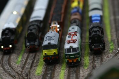 Widoczne są modele pociągów ustawione na torach kolejowych, które składają się na makiety kolejowe. Lokomotywy i wagony mają różne barwy i wygląd, prezentując różnorodność taboru kolejowego. Kompozycja modeli tworzy scenę typową dla stacji kolejowej z różnymi składami pociągów gotowych do odjazdu.