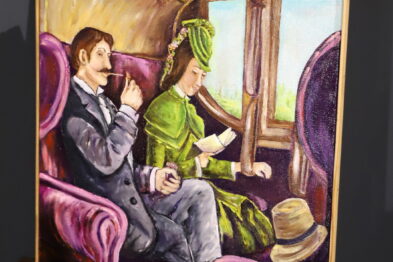Obraz przedstawia dwójkę pasażerów podróżujących pociągiem: siedzącą kobietę w zielonym stroju i czytającego mężczyznę w garniturze. Wnętrze wagonu jest stylizowane na epokę, z fioletowymi fotelami i drewnianymi elementami. Przez okno widać zewnętrzny krajobraz, sugerujący szybką jazdę.