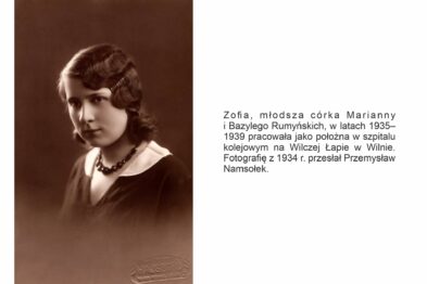 Widoczne jest czarno-białe zdjęcie kobiety z lat 30. XX wieku, która ma elegancką fryzurę i ubrana jest w ciemną bluzkę z lekko marszczonym dekoltem. Na dole obrazu znajduje się opis informujący o tożsamości kobiety, jej związku z kolejnictwem oraz miejscem pracy.