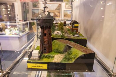W gablocie wystawowej umieszczony jest model kolejowy przedstawiający scenerię z wieżą ciśnień, domkiem oraz torami. Wieża ciśnień pokryta jest cegłą, ma u góry liczne okna i stożkowy dach, a obok znajduje się mniejszy budynek z podobnym dachem. Dookoła rozmieszczone są elementy krajobrazu takie jak trawa i krzewy, a całość kompozycji tworzy realistyczną miniaturę.