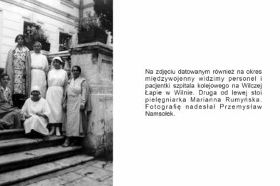 Grupa osób stoi na schodach przed budynkiem, który może być instytucją lub stacją. Kobiety ubrane są w białe uniformy pielęgniarskie; jedna siedzi na stopniach, pozostałe stoją. W tle widoczne są kolumny i drzwi, które sugerują wejście do obiektu.