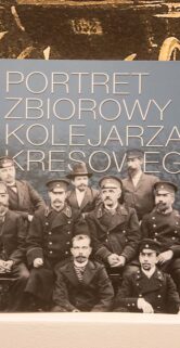 Grupa mężczyzn w mundurach kolejowych pozuje do zdjęcia grupowego; ich wyraz twarzy sugeruje powagę i dumę z wykonywanej służby. Przed nimi widoczna jest książka z tytułem odnoszącym się do ich portretu. W tle widać czarno-białą fotografię z wizerunkiem starego parowozu.