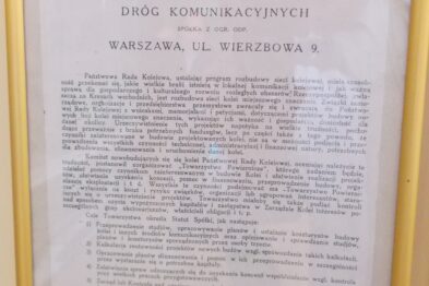 Zdjęcie przedstawia zawieszony na ścianie w ramie dokument z tekstem, który wydaje się być starym drukiem lub statutem. U góry widoczne są słowa 