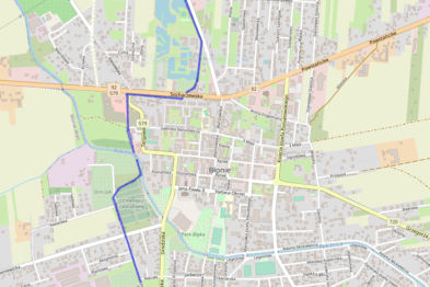 Mapa przedstawia schematyczną sieć dróg, linii kolejowych oraz układ urbanistyczny miasta. Kolorowe linie reprezentują różne trasy, wśród których widoczne są również linie kolejowe. W centralnej części widoczne jest zagęszczenie ulic i dróg, co sugeruje miejski obszar o większej gęstości zabudowy.