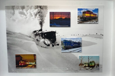 Eksponat przedstawia zbiór pięciu fotografii o tematyce kolei w zimie. Większa, centralna fotografia pokazuje parowóz wydobywający gęste kłęby białego dymu w śnieżnym otoczeniu. Pozostałe mniejsze zdjęcia ukazują pociągi i tory kolejowe oświetlone w nocnych warunkach, z widocznymi efektami działania niskich temperatur.