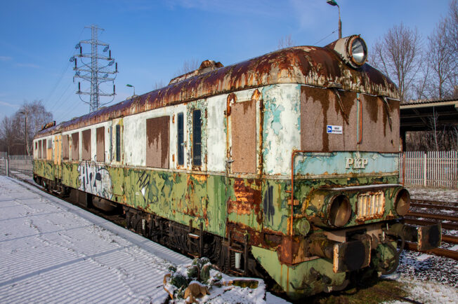 Jest to stary wagon motorowy oznaczony numerem SN61-133 na torach kolejowych. Widać, że jego karoseria jest mocno skorodowana, a farba miejscami odpada. Pojazd jest pokryty graffiti, co wskazuje na dłuższy czas postojenia w jednym miejscu.