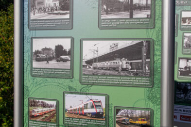 Tablica informacyjna z fotografiami i tekstami przedstawia historię kolei i jej wpływ na rozwój Mazowsza. Na dole tablicy znajduje się grafika pociągu oraz informacje o wydarzeniu związane z koleją. Tło tablicy jest zielone, a na jej górnej krawędzi widnieje logo sponsora.
