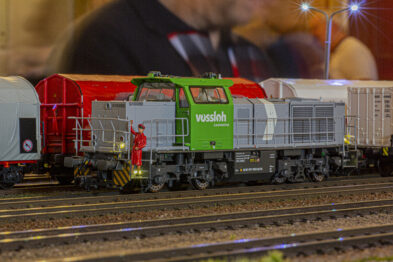 Na zdjęciu widoczna jest makieta kolejowa prezentująca zieloną lokomotywę oznaczoną logo 