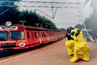 Zdjęcie fotografii z pociągiem. Na pierwszym planie widoczna figurka ludzika z plasteliny.