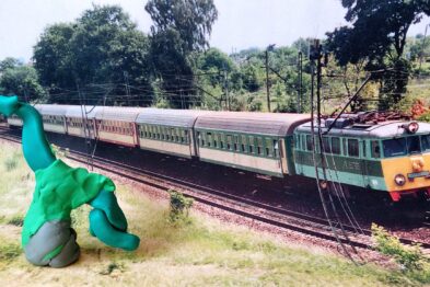 Zdjęcie fotografii z pociągiem. Na pierwszym planie widoczna figurka ludzika z plasteliny.