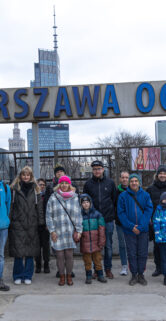 Zdjęcie grupowe uczestników spaceru pod tablicą z nazwą przystanku Warszawa Ochota
