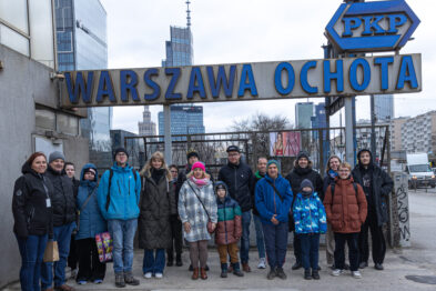 Zdjęcie grupowe uczestników spaceru pod tablicą z nazwą przystanku Warszawa Ochota