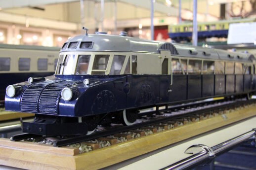 Model niebiesko_kremowego pociągu. Model stoi na drewnianej podstawie.