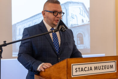 Osoba przemawiająca na scenie podczas konferencji.