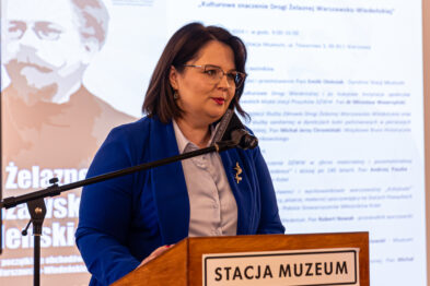 Osoba przemawiająca na scenie podczas konferencji.