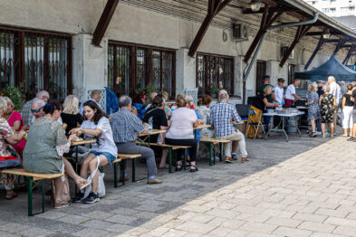 duża grupa ludzi je obiad przy ławkach