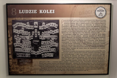 Plansza wystawowa upamiętniająca 140-lecie Drogi Żelaznej Iwangrodzko-Dąbrowskiej, znajdująca się w Stacji Muzeum. W tle historyczne zdjęcie kolejarzy. Tytuł planszy: „Ludzie kolei