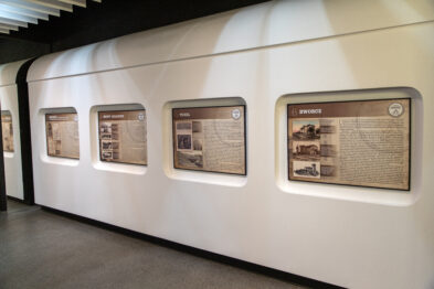 Biała ściana z powieszonymi na niej planszami wystawy