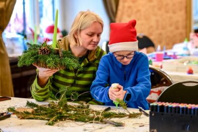 Pani robiąca z dzieckiem stroik świąteczny