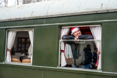 Mężczyzna w czapce św. Mikołaja wygląda przez okno wagonu