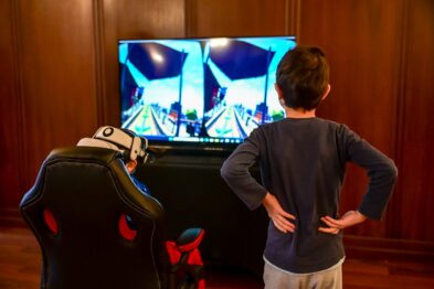 Dziecko w goglach vr na głowie siedzi na krześle przed telewizorem