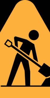 Żółty trójkąt na czarnym tle. W środku ikona człowieka z łopatą