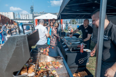 Catering serwuje potrawy z grilla podczas plenerowego wydarzenia w Stacji Muzeum.
