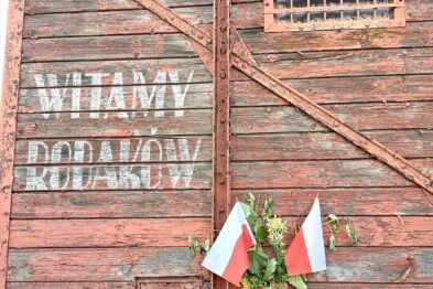 Wagon towarowy z polskimi flagami i napisem Witamy Rodaków
