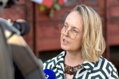 Kobieta udzielająca wywiadu do telewizji na tle wagonu towarowego